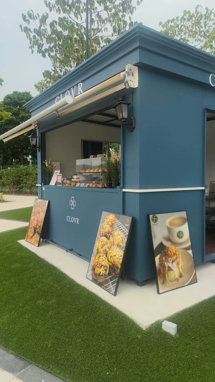 CLOVR navy micro-kiosk with white awning on the Eco Grandeur Village lawn